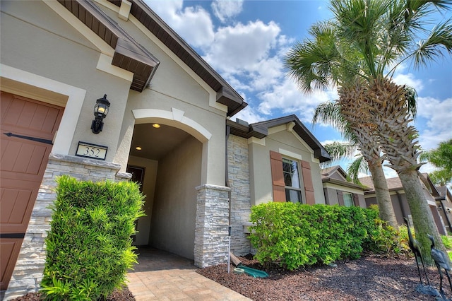 entrance to property featuring stucco siding and stone siding