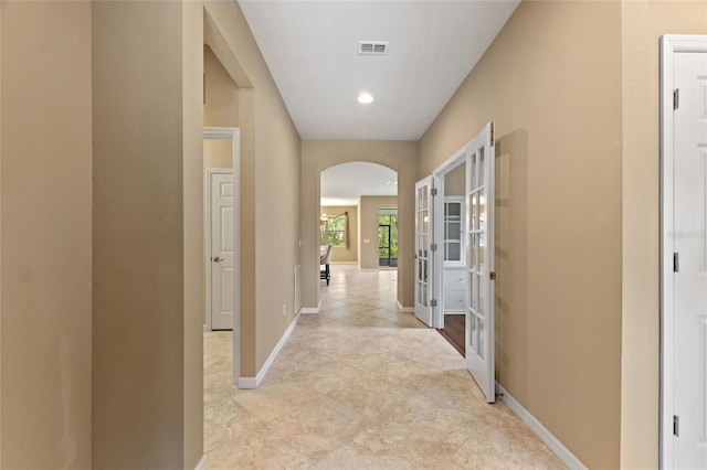 hall with arched walkways, baseboards, light tile patterned floors, french doors, and recessed lighting