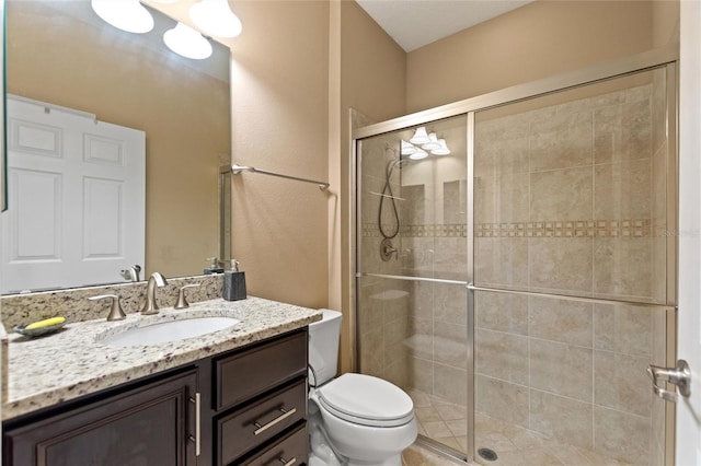 bathroom with a stall shower, vanity, and toilet