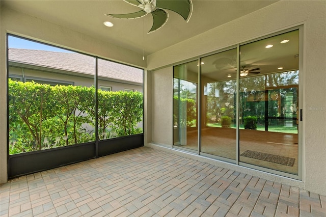 unfurnished sunroom featuring a ceiling fan and plenty of natural light