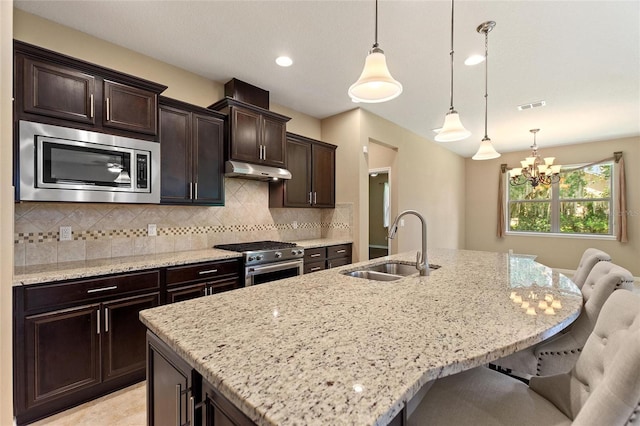 kitchen with stainless steel appliances, a sink, under cabinet range hood, a chandelier, and a kitchen breakfast bar