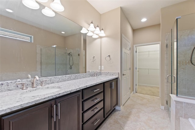 full bath featuring a stall shower, a spacious closet, double vanity, and recessed lighting