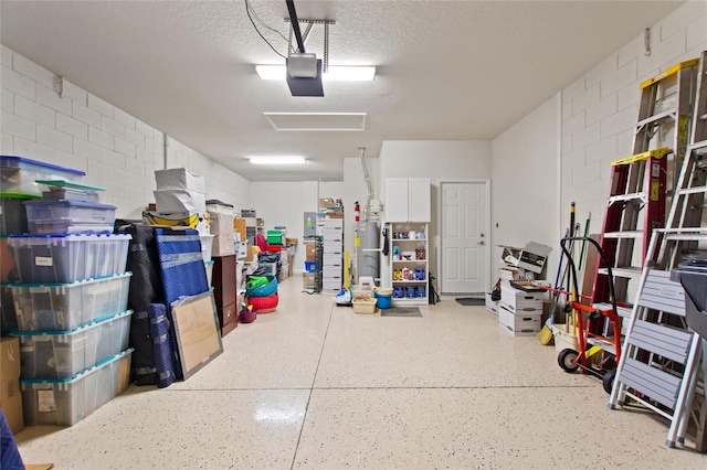 garage with concrete block wall, a garage door opener, and water heater