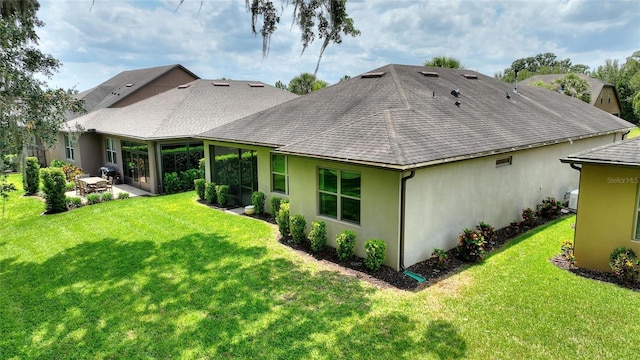 back of house featuring stucco siding, a lawn, a shingled roof, and a patio