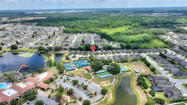 view of property location with nearby suburban area, a nearby body of water, and a forest