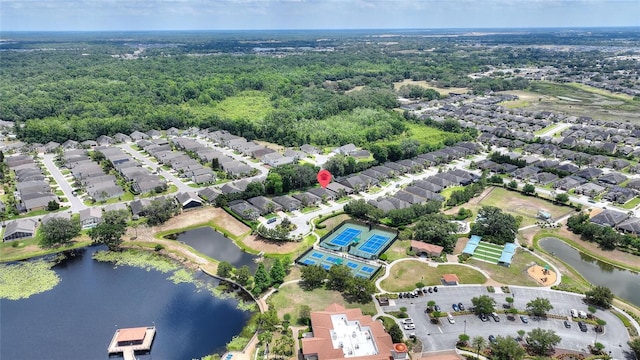 aerial view of property's location featuring a large body of water, nearby suburban area, and a heavily wooded area