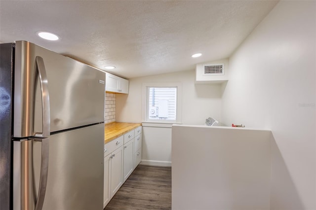 1007 11th St, Saint Cloud, FL 34769 - kitchen featuring freestanding refrigerator, white cabinets, visible vents, dark wood-style flooring, and decorative backsplash