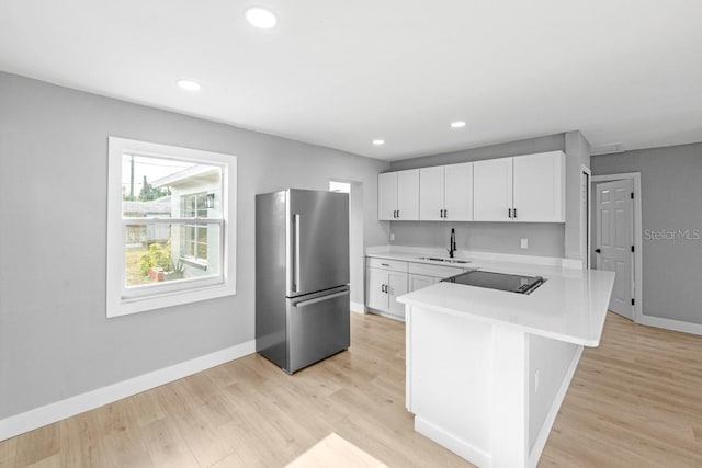 4445 Stuart Ave, Titusville, FL 32780 - kitchen featuring freestanding refrigerator, a peninsula, a sink, baseboards, and light countertops
