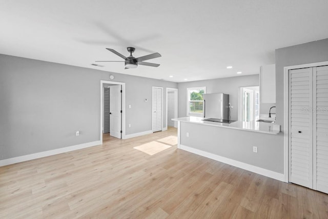 4445 Stuart Ave, Titusville, FL 32780 - unfurnished living room with a ceiling fan, light wood-type flooring, baseboards, recessed lighting, and a sink