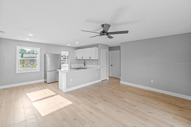 4445 Stuart Ave, Titusville, FL 32780 - kitchen featuring freestanding refrigerator, light countertops, ceiling fan, open floor plan, and white cabinetry