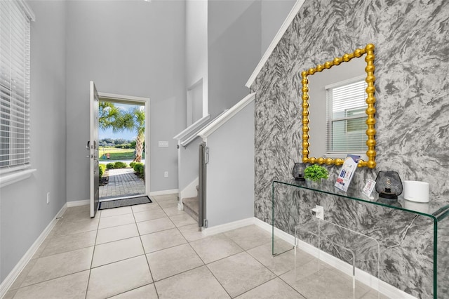 tiled foyer with a towering ceiling, stairs, and baseboards