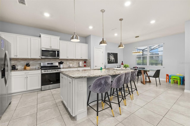 kitchen featuring stainless steel appliances, tasteful backsplash, light tile patterned flooring, recessed lighting, and light stone countertops