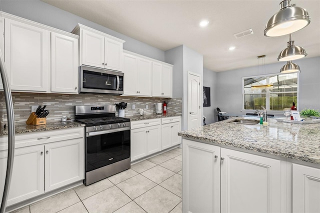 kitchen featuring appliances with stainless steel finishes, a sink, tasteful backsplash, white cabinets, and light tile patterned floors