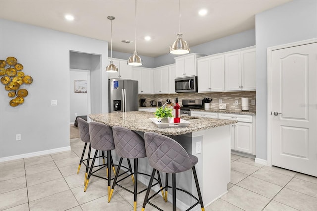 kitchen with appliances with stainless steel finishes, backsplash, light tile patterned flooring, a kitchen breakfast bar, and white cabinetry