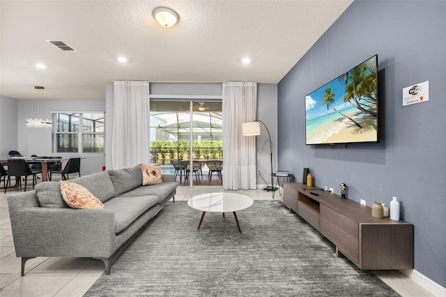 tiled living area featuring healthy amount of natural light, recessed lighting, a chandelier, and a textured ceiling