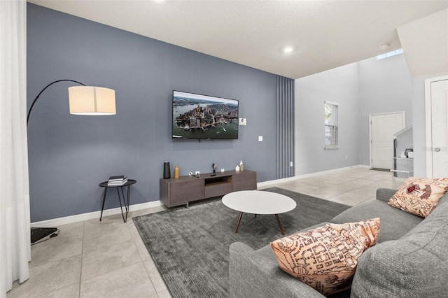 tiled living area with baseboards and a high ceiling