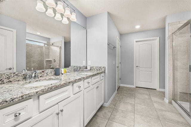 bathroom featuring a stall shower, double vanity, baseboards, tile patterned flooring, and recessed lighting