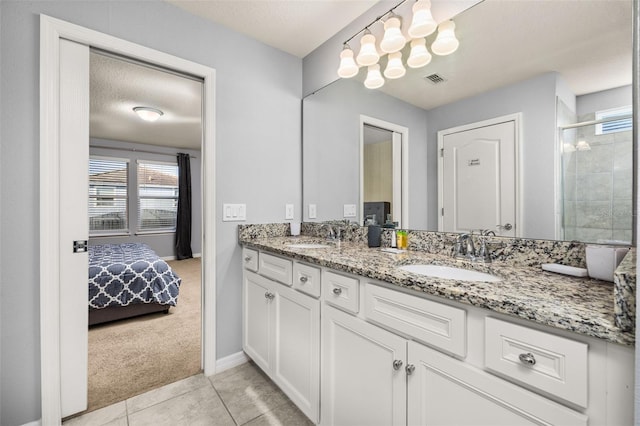 ensuite bathroom featuring baseboards, tiled shower, double vanity, and tile patterned floors