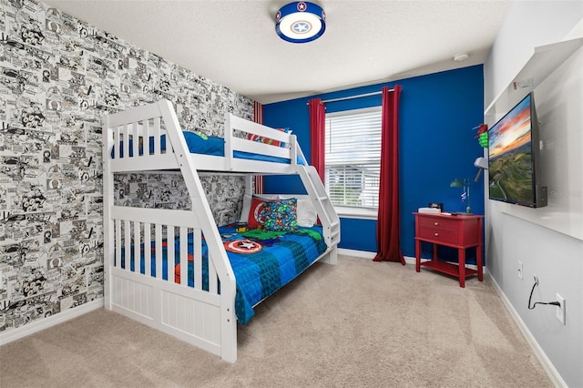 carpeted bedroom with wallpapered walls, a textured ceiling, baseboards, and an accent wall