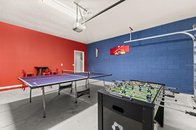 recreation room featuring concrete flooring, a textured ceiling, and concrete block wall