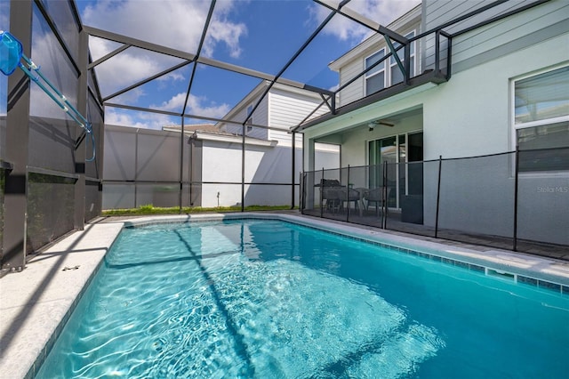 view of swimming pool featuring a patio, glass enclosure, and a ceiling fan