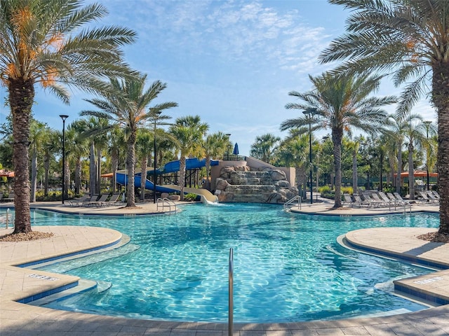 community pool with a water slide and a patio