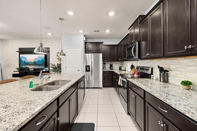 kitchen with appliances with stainless steel finishes, a sink, light tile patterned floors, light stone countertops, and tasteful backsplash