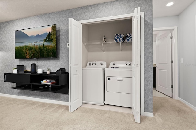 washroom featuring washer and clothes dryer, light carpet, and baseboards