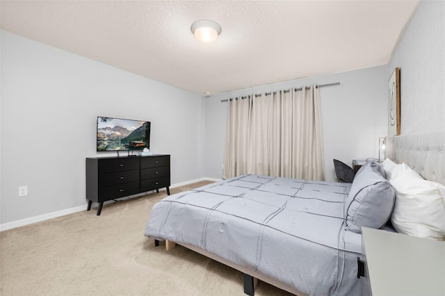 bedroom featuring light colored carpet, a textured ceiling, and baseboards