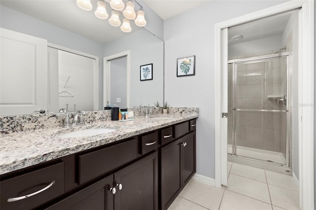 full bathroom with tile patterned floors, a stall shower, double vanity, and baseboards