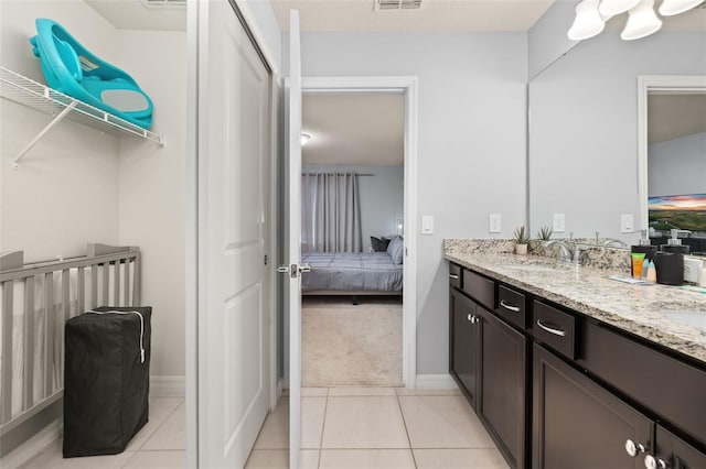 ensuite bathroom featuring double vanity, tile patterned flooring, and baseboards