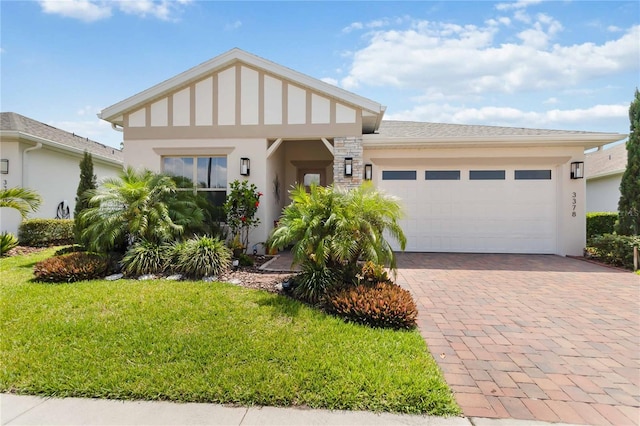 view of front of property featuring a front yard, stucco siding, a garage, and decorative driveway