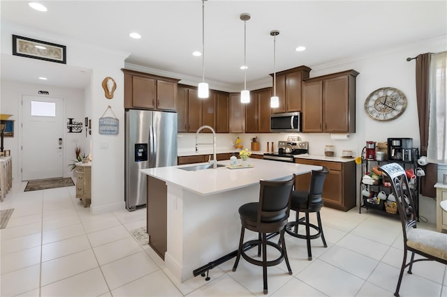 kitchen with stainless steel appliances, a sink, light countertops, an island with sink, and hanging light fixtures