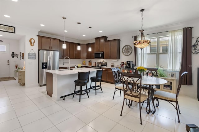 kitchen featuring stainless steel appliances, a sink, light countertops, pendant lighting, and recessed lighting