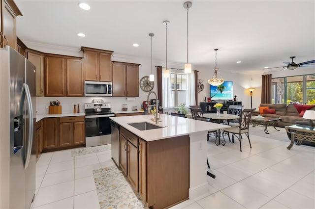 kitchen with appliances with stainless steel finishes, a sink, light tile patterned floors, brown cabinetry, and open floor plan