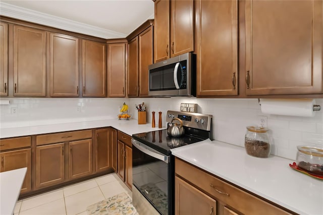 kitchen with stainless steel appliances, tasteful backsplash, light countertops, light tile patterned floors, and ornamental molding