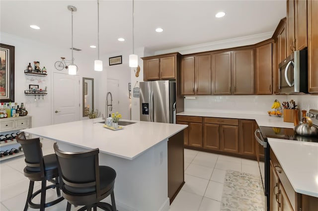 kitchen with appliances with stainless steel finishes, a sink, light countertops, a center island with sink, and a kitchen breakfast bar