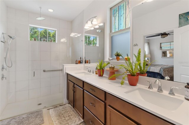 full bath featuring a tile shower, connected bathroom, double vanity, and a ceiling fan