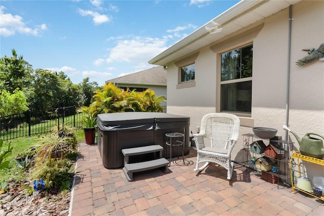 view of patio with a hot tub and fence