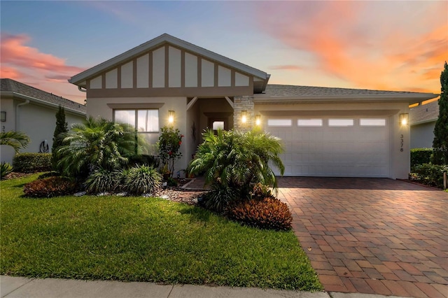 view of front of home with an attached garage, a yard, decorative driveway, and stucco siding