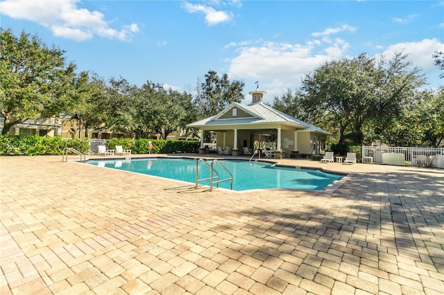 community pool with fence and a patio