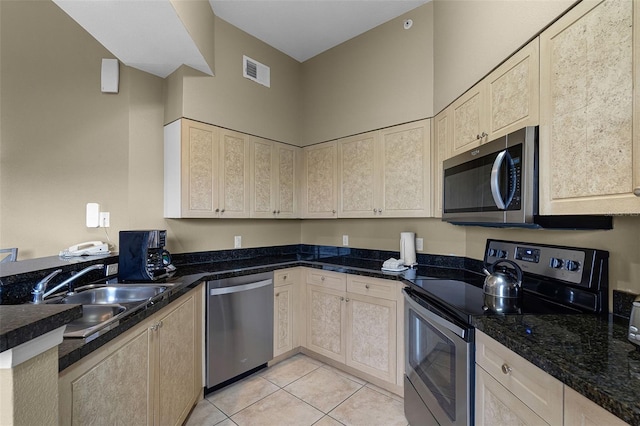 kitchen with a sink, dark stone counters, light tile patterned flooring, visible vents, and appliances with stainless steel finishes