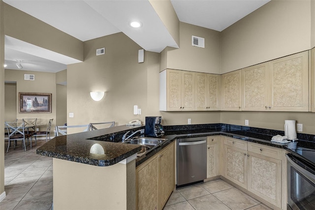 kitchen with stainless steel appliances, a peninsula, light tile patterned floors, a sink, and cream cabinetry