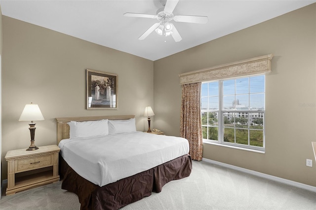 bedroom featuring light colored carpet, baseboards, and a ceiling fan