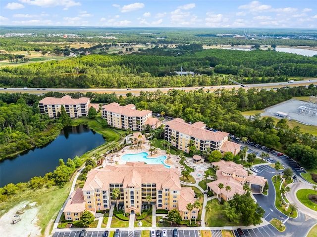 aerial overview of property's location with a nearby body of water, apartment complex, and a pool area