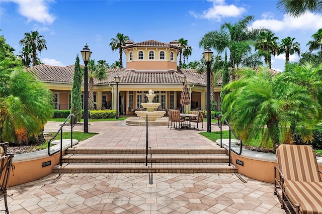 rear view of house with a patio, a tile roof, and stucco siding