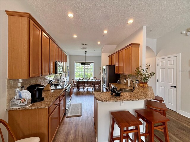 2287 Park Maitland Ct, Maitland, FL 32751 - kitchen featuring a breakfast bar area, a sink, stainless steel appliances, tasteful backsplash, and light stone counters
