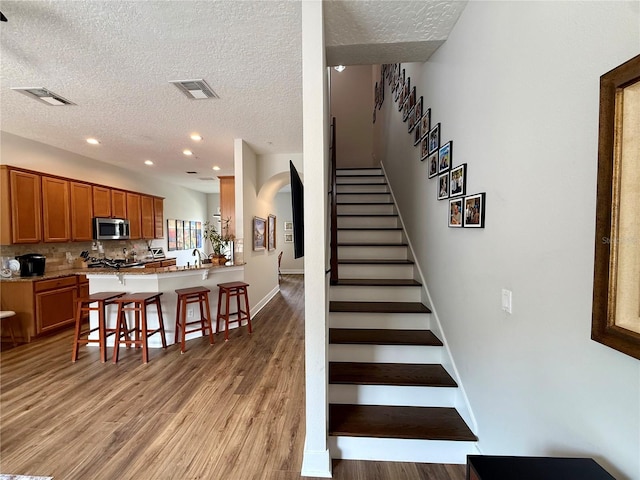 2287 Park Maitland Ct, Maitland, FL 32751 - stairway featuring a textured ceiling, visible vents, wood finished floors, and arched walkways