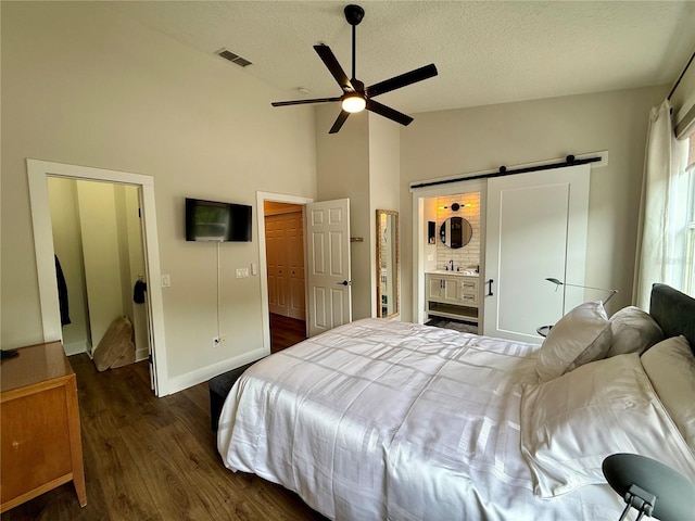 2287 Park Maitland Ct, Maitland, FL 32751 - bedroom with a textured ceiling, a barn door, high vaulted ceiling, visible vents, and dark wood-style floors