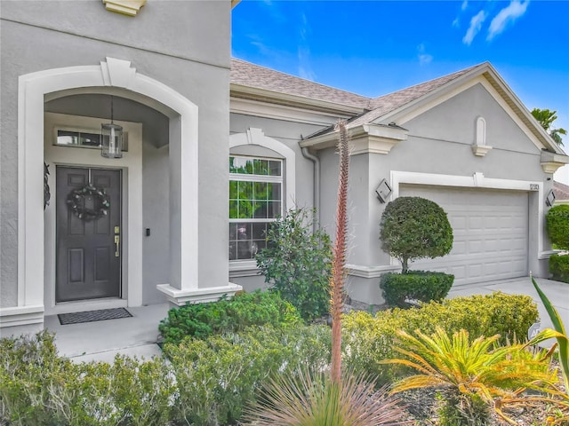 12313 Prairie Plantation Way, Orlando, FL 32824 - doorway to property featuring stucco siding, an attached garage, a shingled roof, and concrete driveway